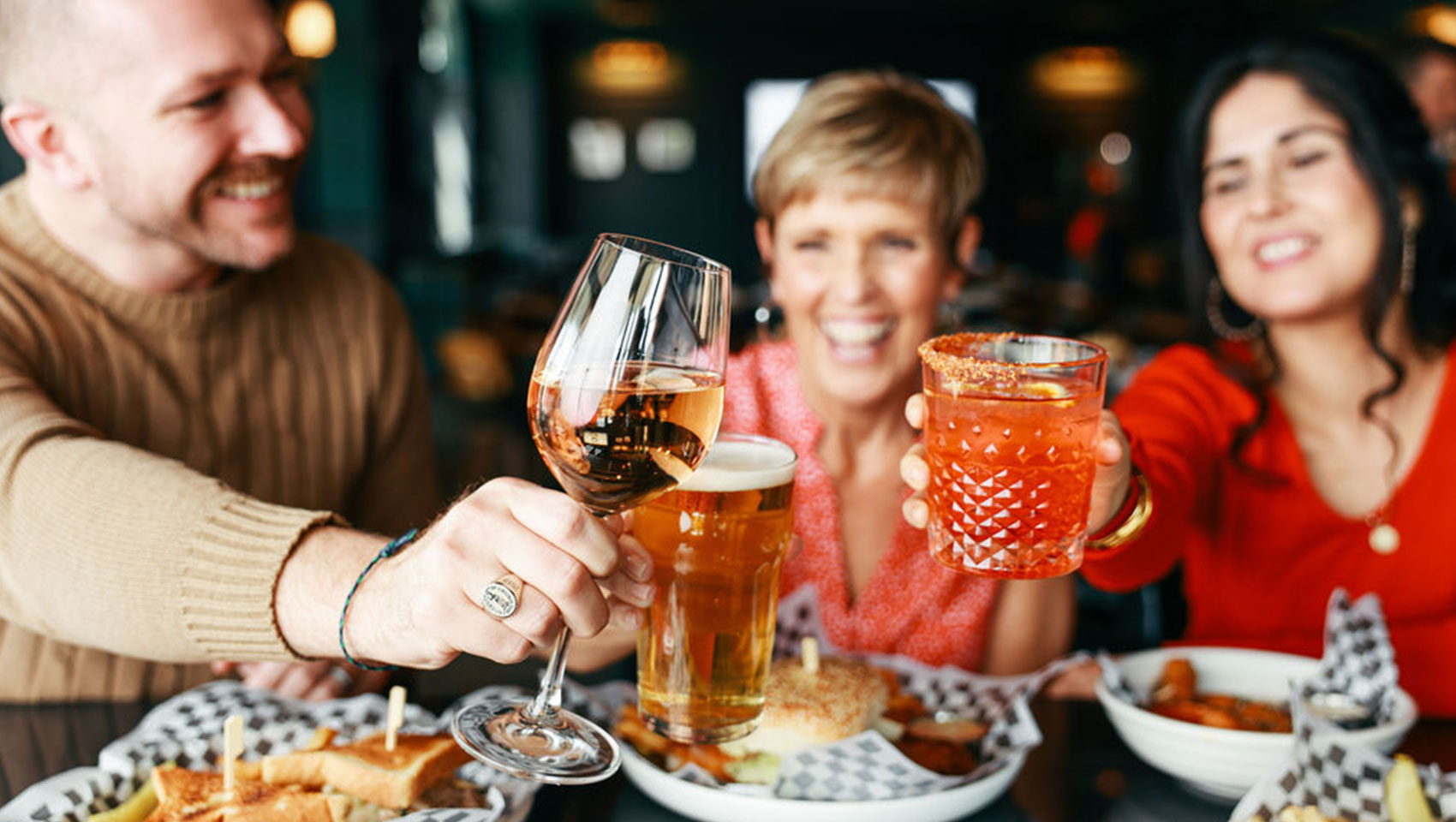 friends toasting and smiling at dinner at The Good Sport