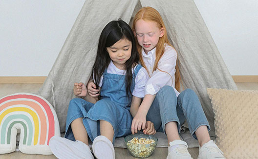 two kids eating popcorn in a tent